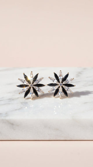 Pair of star-shaped earrings on a marble surface with a light pink background